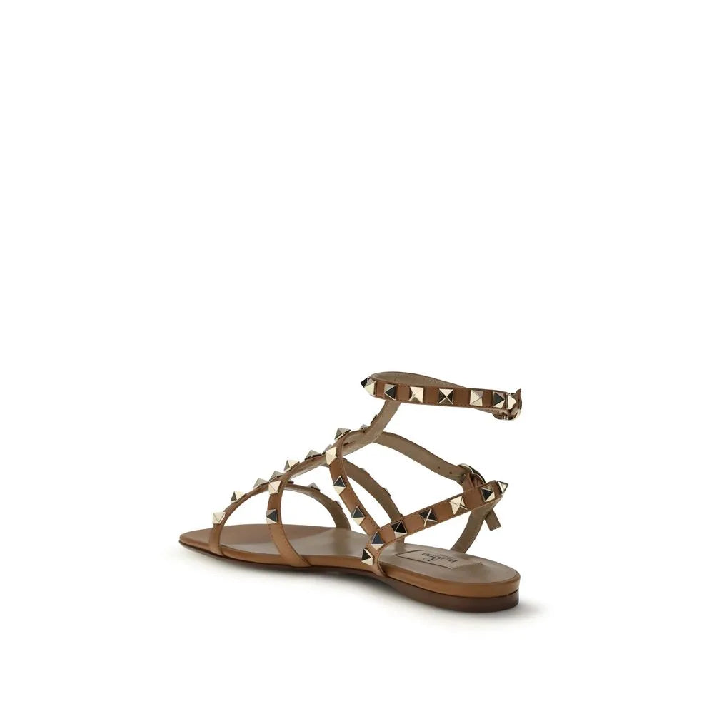 Beige calf leather flat sandals with gold Rockstuds, adjustable ankle strap, and branded insole.