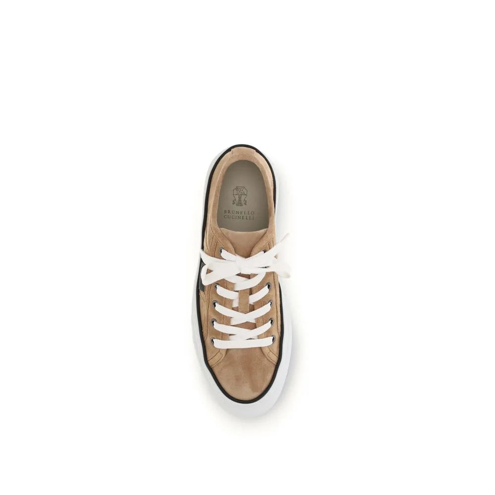 Brunello Cucinelli Shiny Tab beige suede low-top sneaker with white laces, black trim, and a white rubber sole.