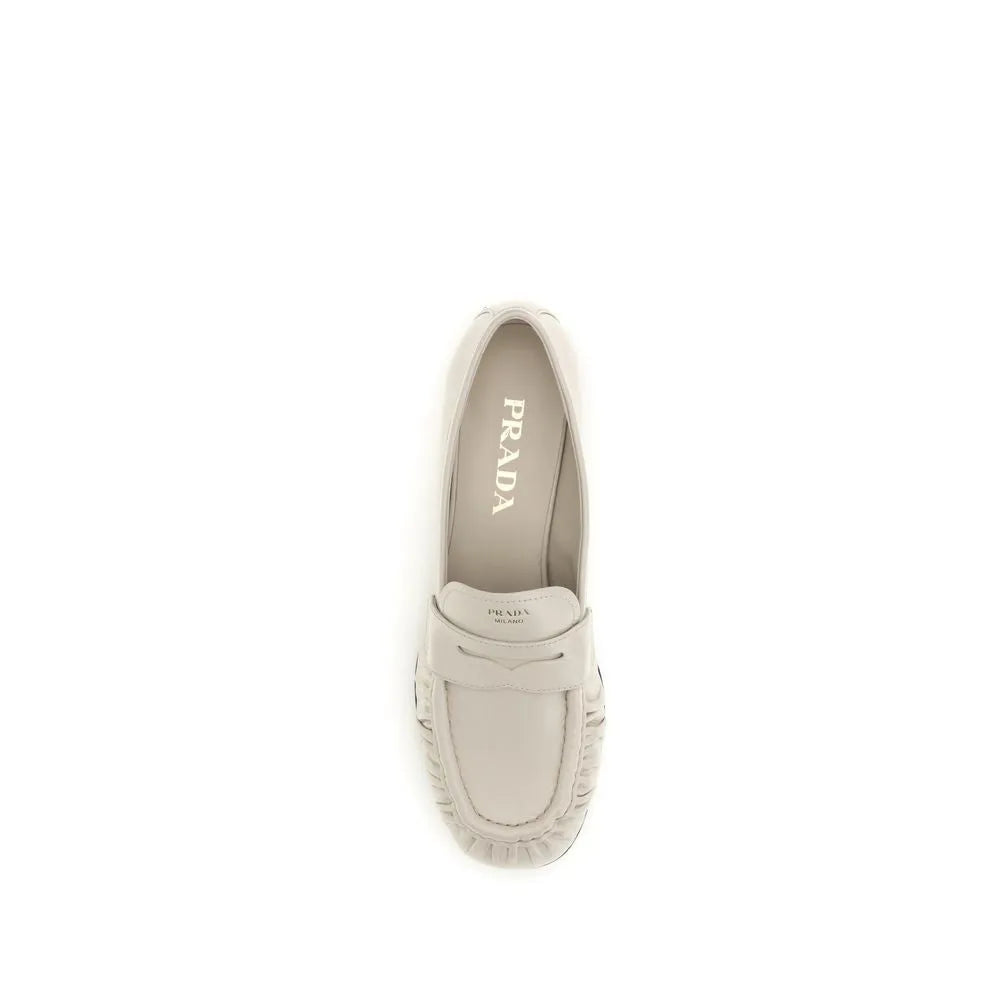 Beige calf leather Prada slip-on loafers with a pleated toe and classic penny strap design.