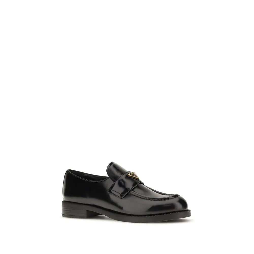 Black glossy calf leather slip-on loafers with a rounded toe and metal triangle logo on the saddle.