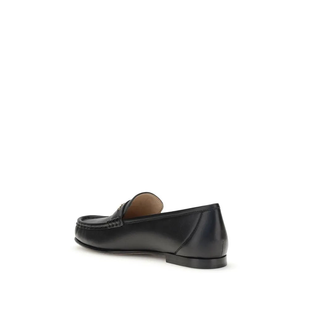 Black polished calf leather slip-on loafers with elegant pleated details and a gold Chloé logo chain.