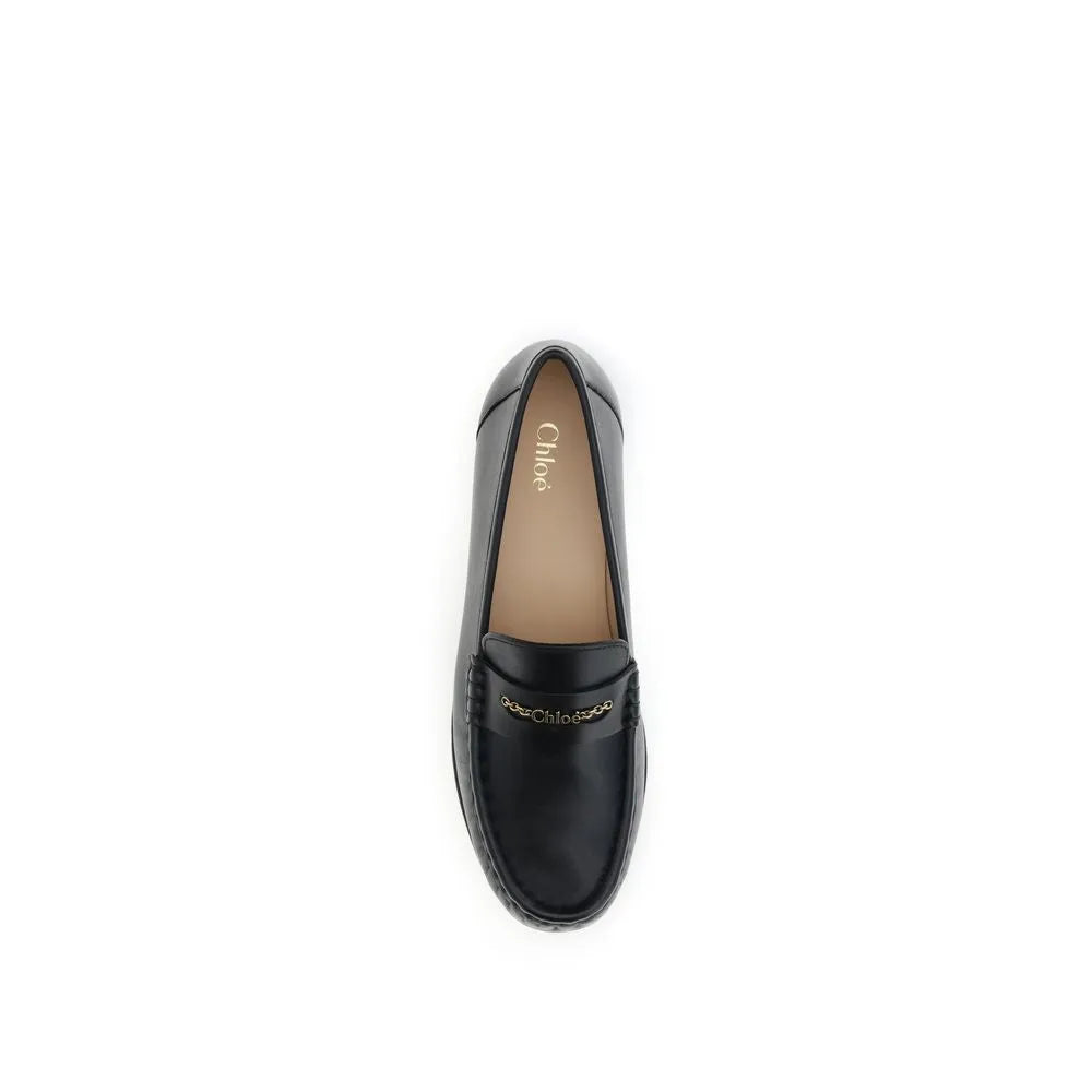 Elegant black polished calf leather Chloé slip-on loafers with a gold chain logo across the vamp.