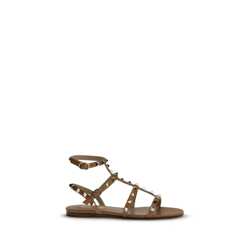 Beige calf leather Valentino Garavani Rockstud flat sandals with gold pyramid studs and adjustable ankle strap.