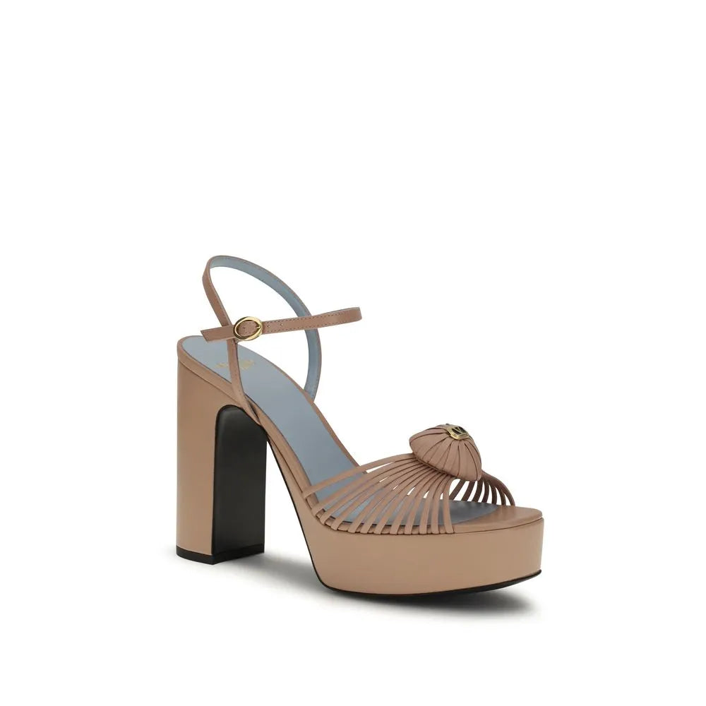 Elegant beige goatskin platform sandals featuring a heart motif, thin toe straps, ankle buckle, and chunky block heel.