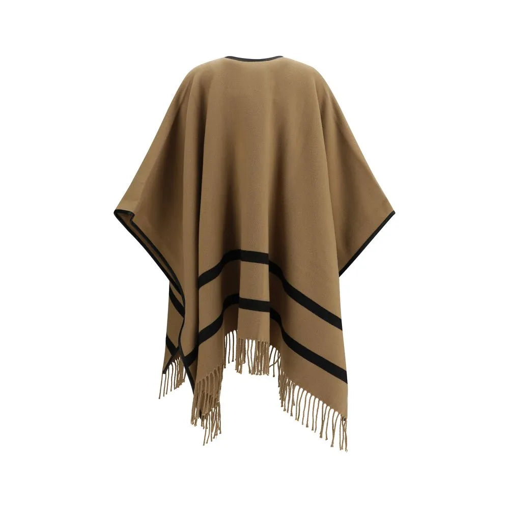 Fluid beige wool poncho with black trim, horizontal stripes, and fringe hem.