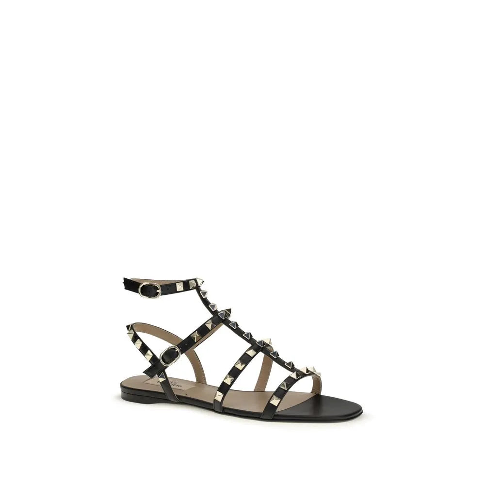 Black calf leather Valentino Garavani Rockstud flat sandals with gold studs and adjustable ankle strap.