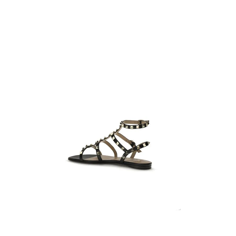 Black calf leather Valentino Garavani Rockstud flat sandals with studded straps and adjustable ankle buckle.