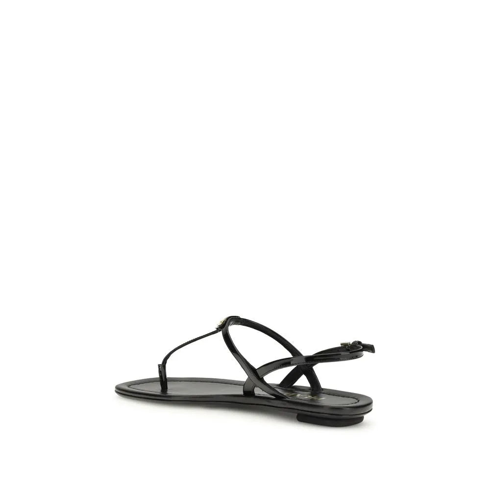 Black patent leather thong flip-flop sandal with gold metal triangle logo and adjustable ankle strap.