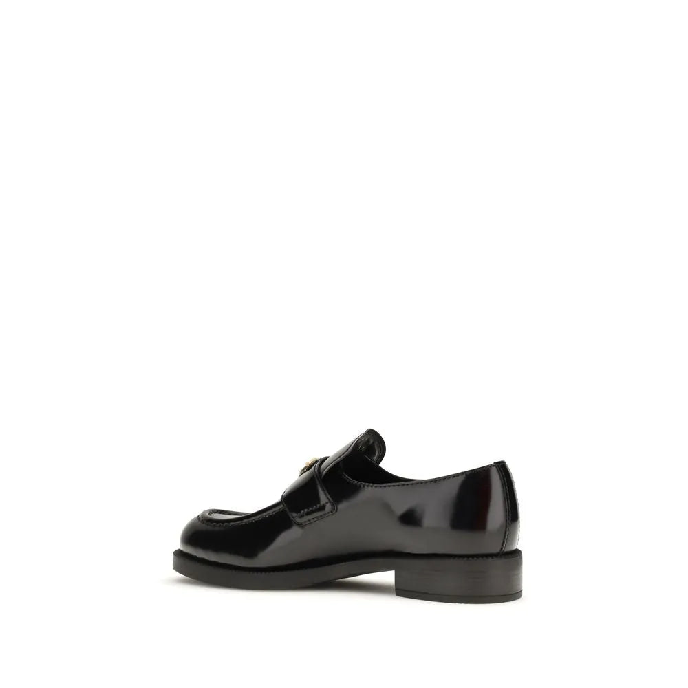 Black glossy calf leather slip-on loafers with rounded toe and iconic metal triangle logo on the saddle.