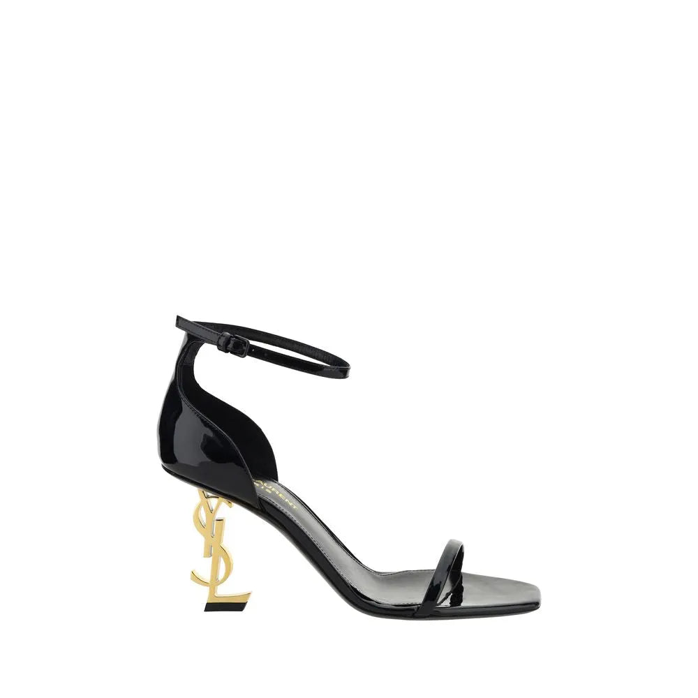 Black patent calf leather Saint Laurent Opyum sandals featuring a gold YSL logo heel, adjustable ankle strap, and open square toe.