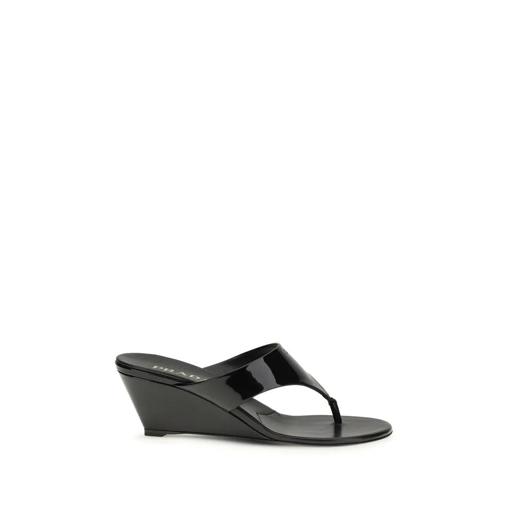 Black patent leather Prada thong wedge sandals with a visible logo on the heel.