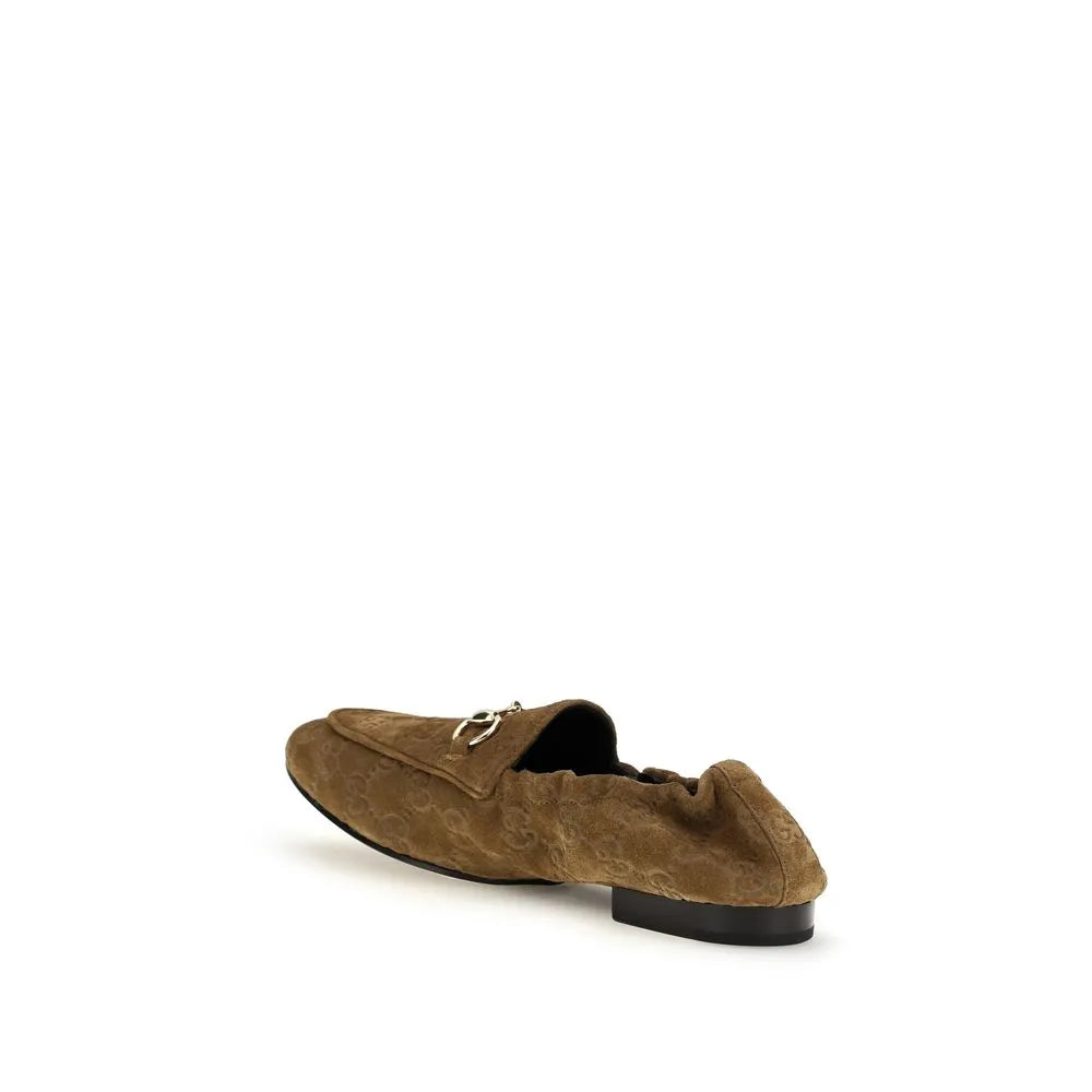 Brown suede slip-on loafers with embossed GG motif, golden horsebit, and elasticized heel.