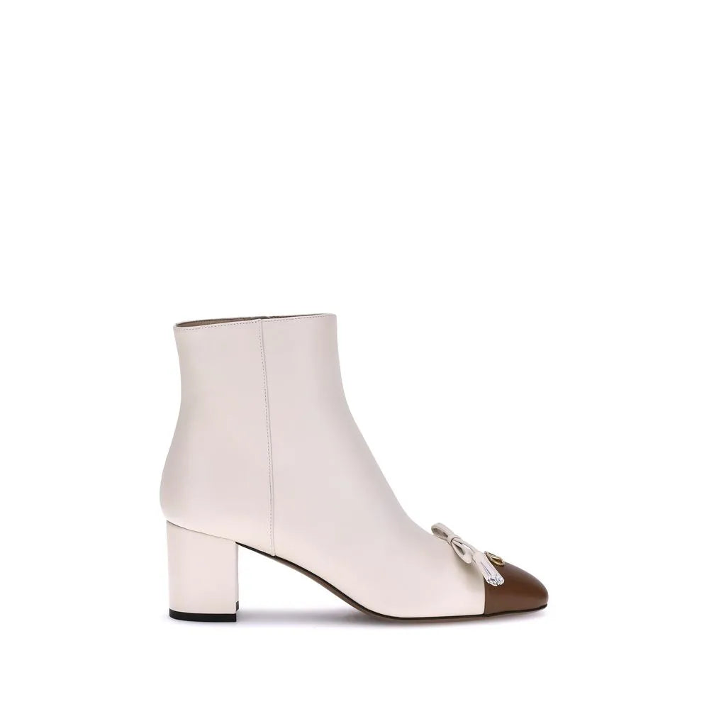 Elegant Valentino Garavani cream goatskin ankle boot with brown toe, VLogo, and leather tassel bow detail.