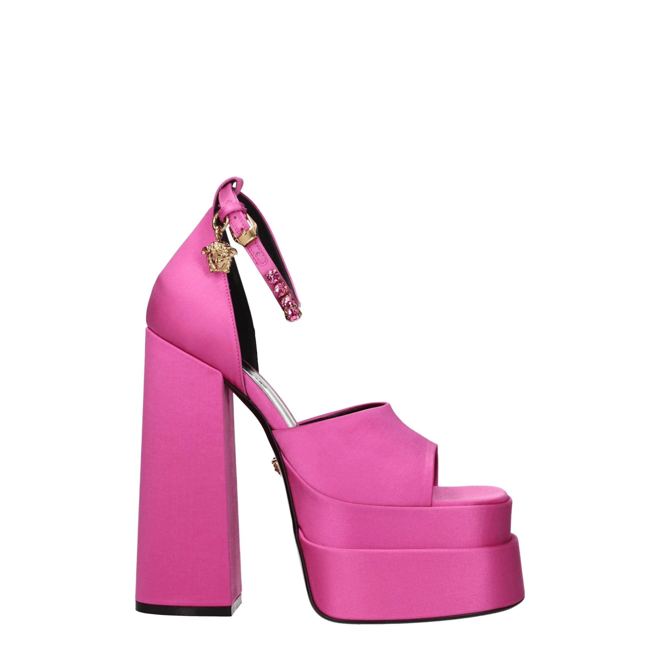 Pink satin platform sandals with open toe, chunky block heel, rhinestone ankle strap, and gold Versace Medusa charm.
