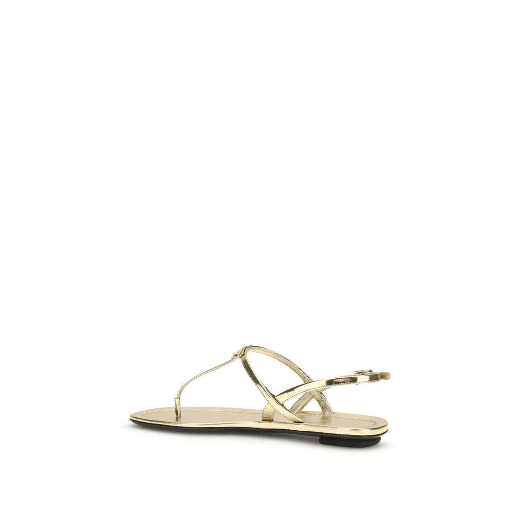 Gold patent leather flat thong sandals with thin straps, adjustable ankle buckle, and black sole.