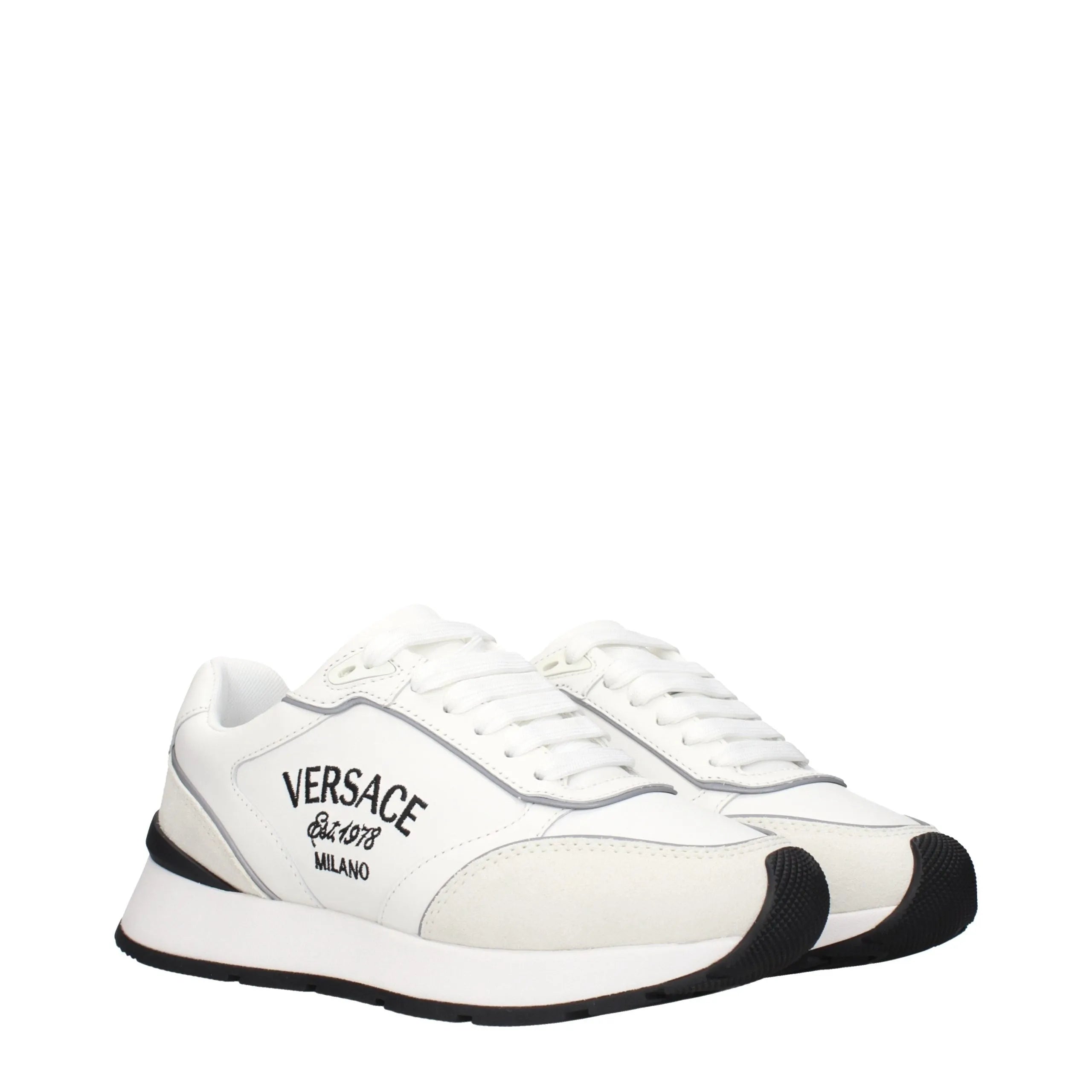 White Versace low-top sneakers in leather and suede, featuring black toe caps, soles, and "VERSACE MILANO" side logo.